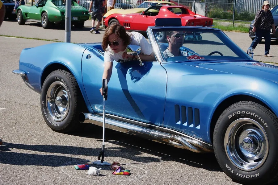Birgit lehnt sich aus der Corvette und sammelt Säcke ein