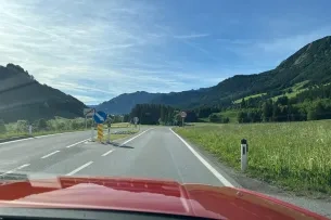 Blick über Motorhaube auf Berge und Ortsausgangsschild